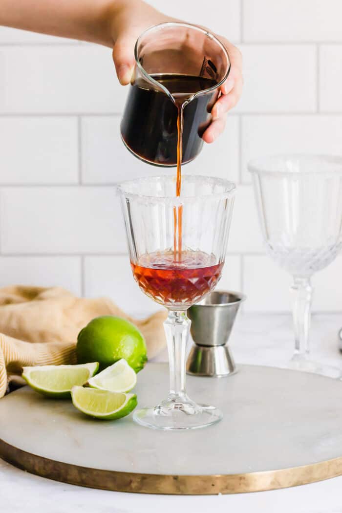 pouring coffee into a stemmed glass with liqueurs