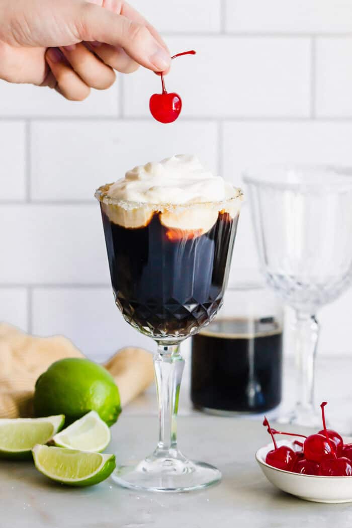 adding a stemmed cherry to the top of a Mexican coffee drink