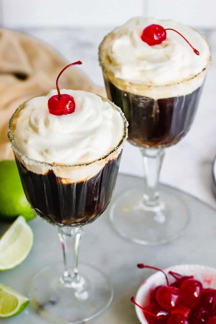 top view of two glasses of a Mexican cocktail made with coffee, liqueurs, whipped cream, and maraschino cherries