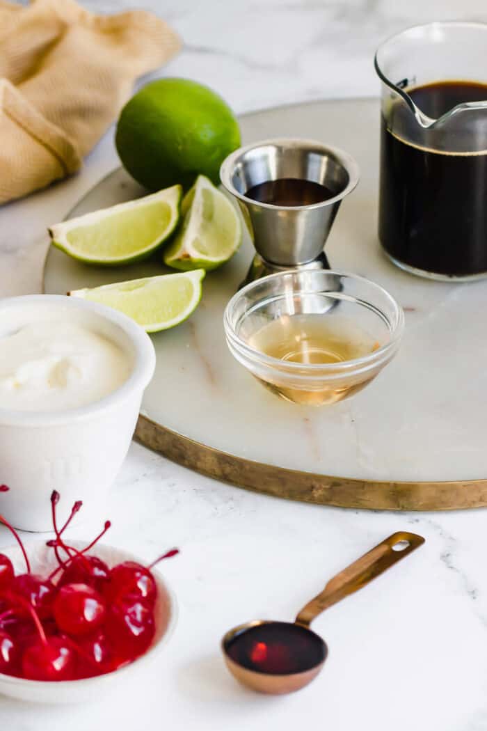 ingredients to make a Mexican cocktail with coffee, liqueurs, whipped cream, and cherries