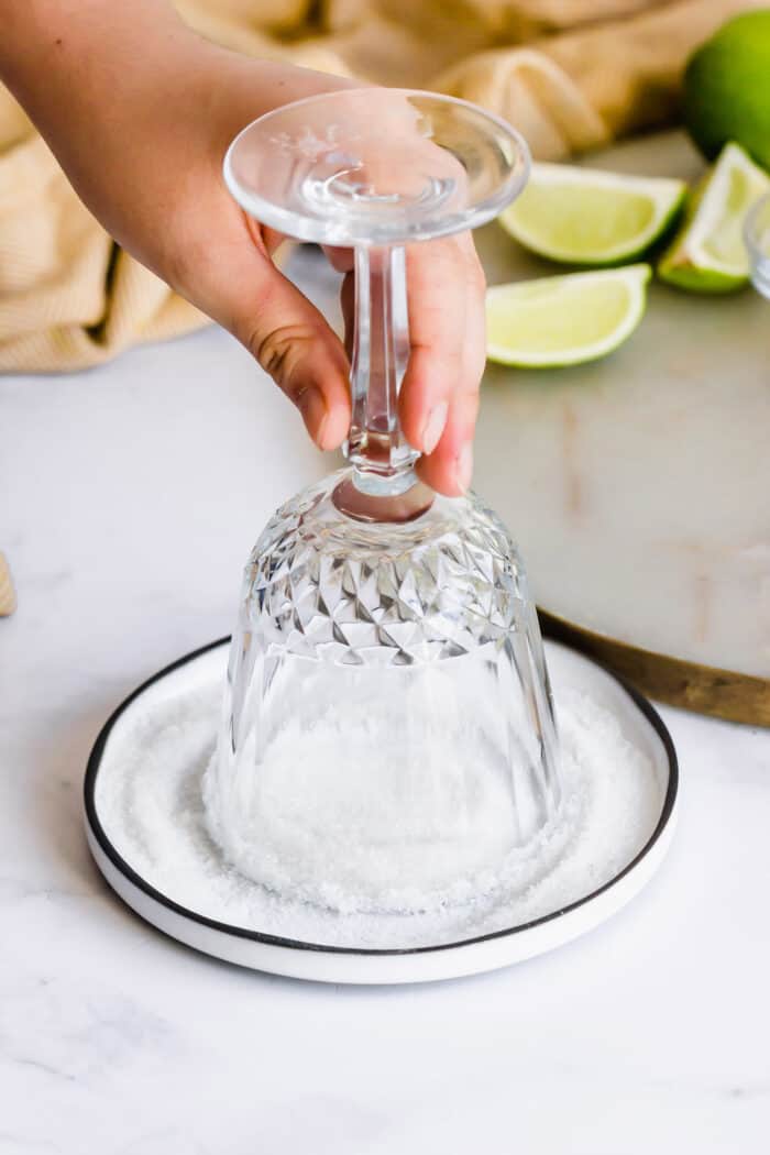 dipping the rim of a stemmed glass into a small plate of sugar