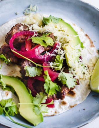 a pork mole taco with avocado, cilantro, and pickled red onions