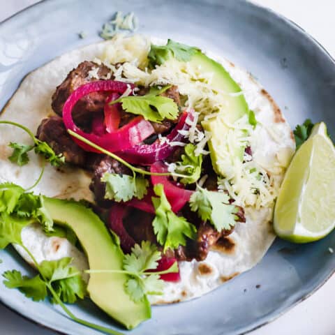 a pork mole taco with avocado, cilantro, and pickled red onions