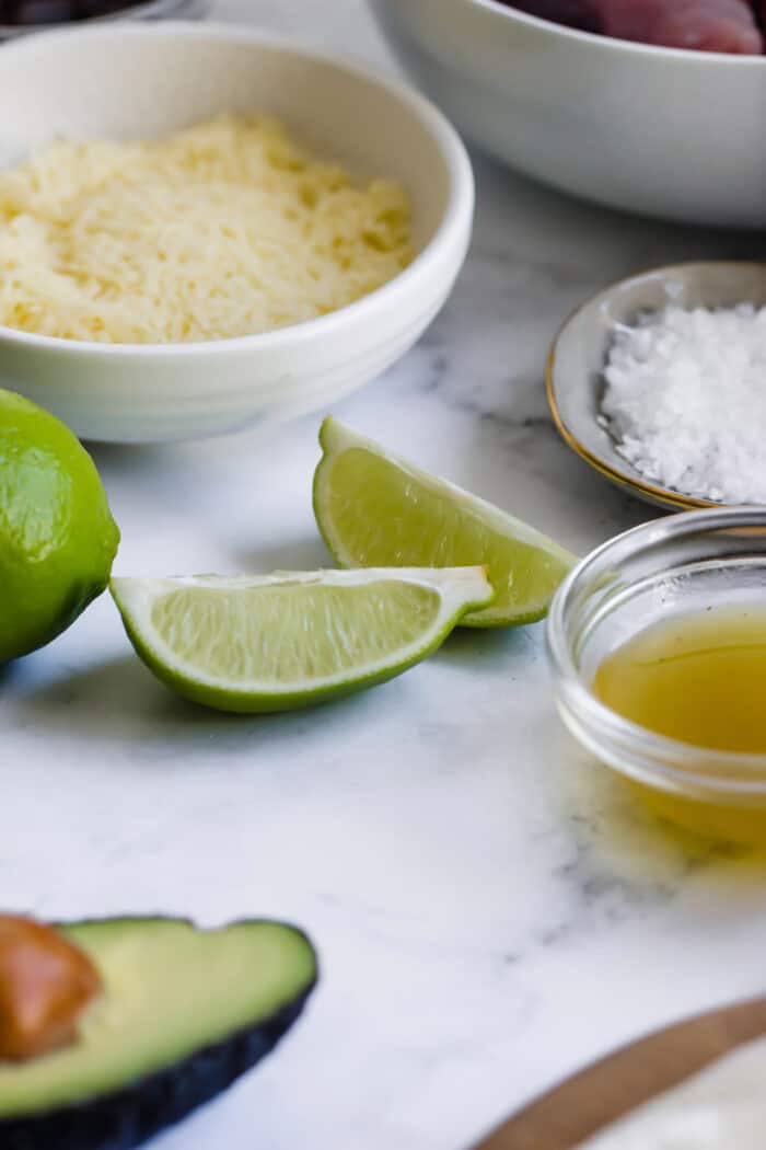 close-up photo of avocados, limes, shredded cheese, and coarse salt