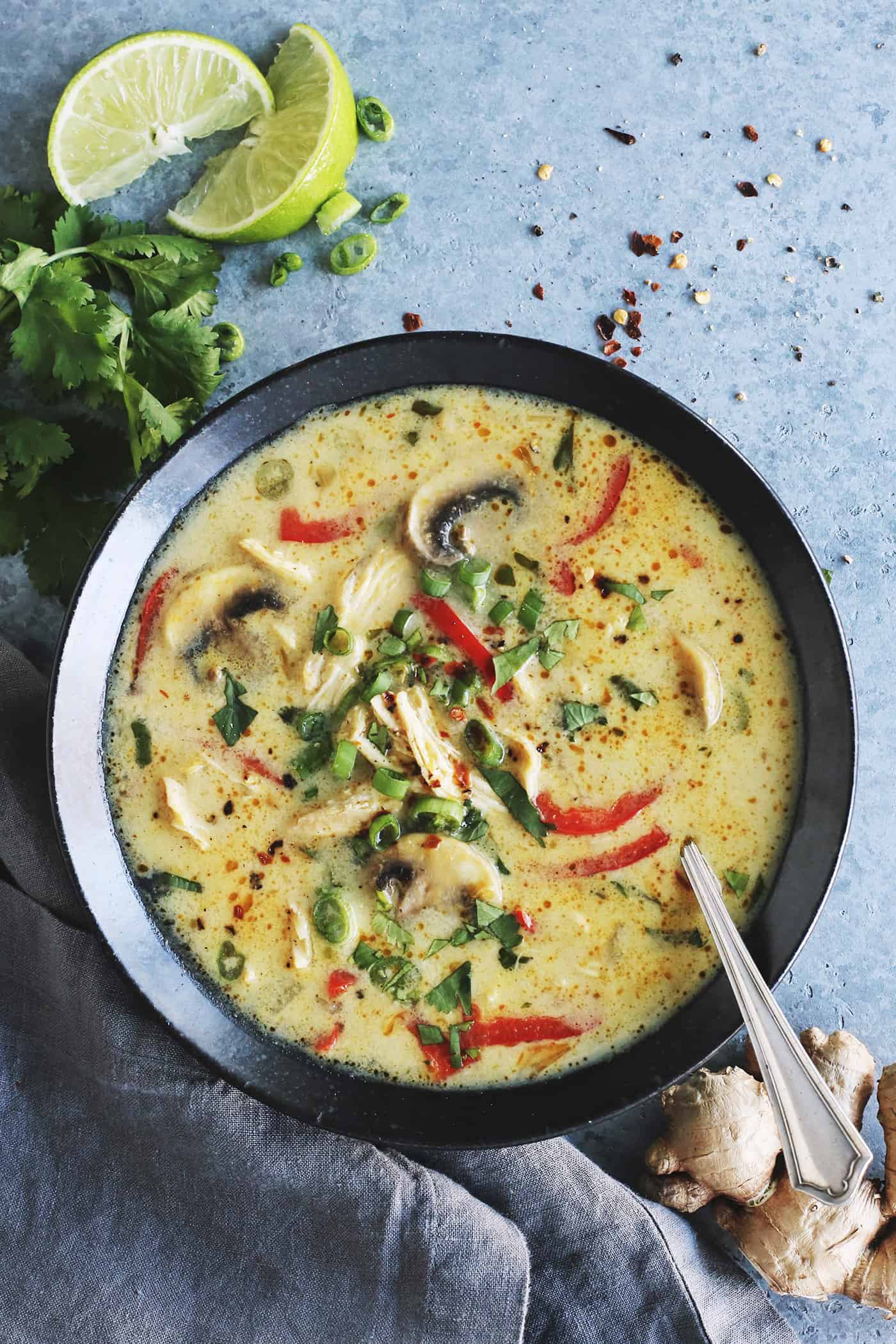 a black bowl full of soup made of coconut milk, curry, chicken, red pepper, and mushrooms