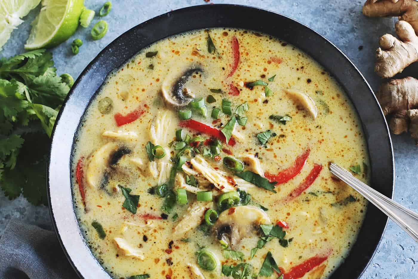 soup in a black bowl, consisting of coconut milk, curry, chicken, mushrooms, and red pepper