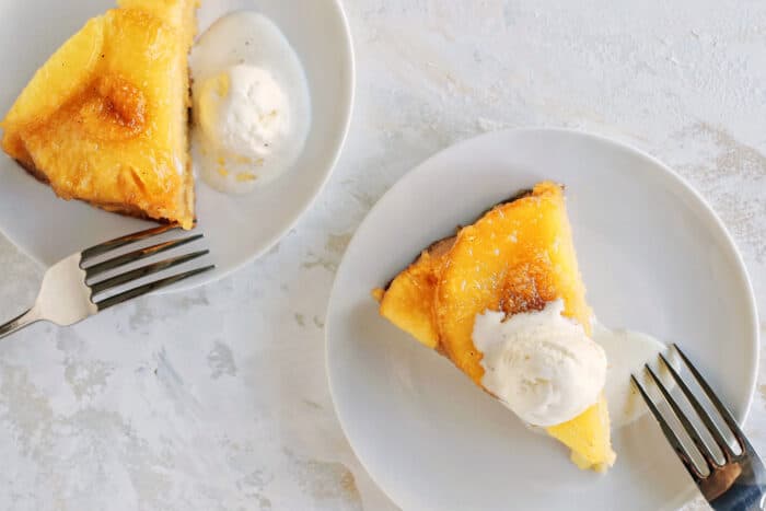 slices of upside-down pineapple cake with scoops of vanilla ice cream on small white plates