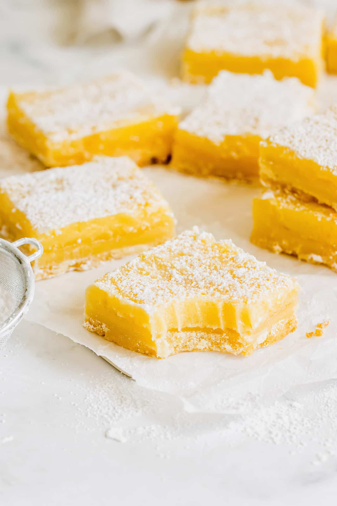 a bite out of a lemon bar, plus more lemon bars in the background