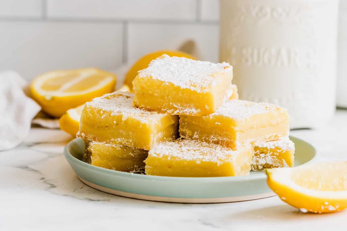 a light green plate with a stack of bars consisting of a shortbread crust and lemon curd filling