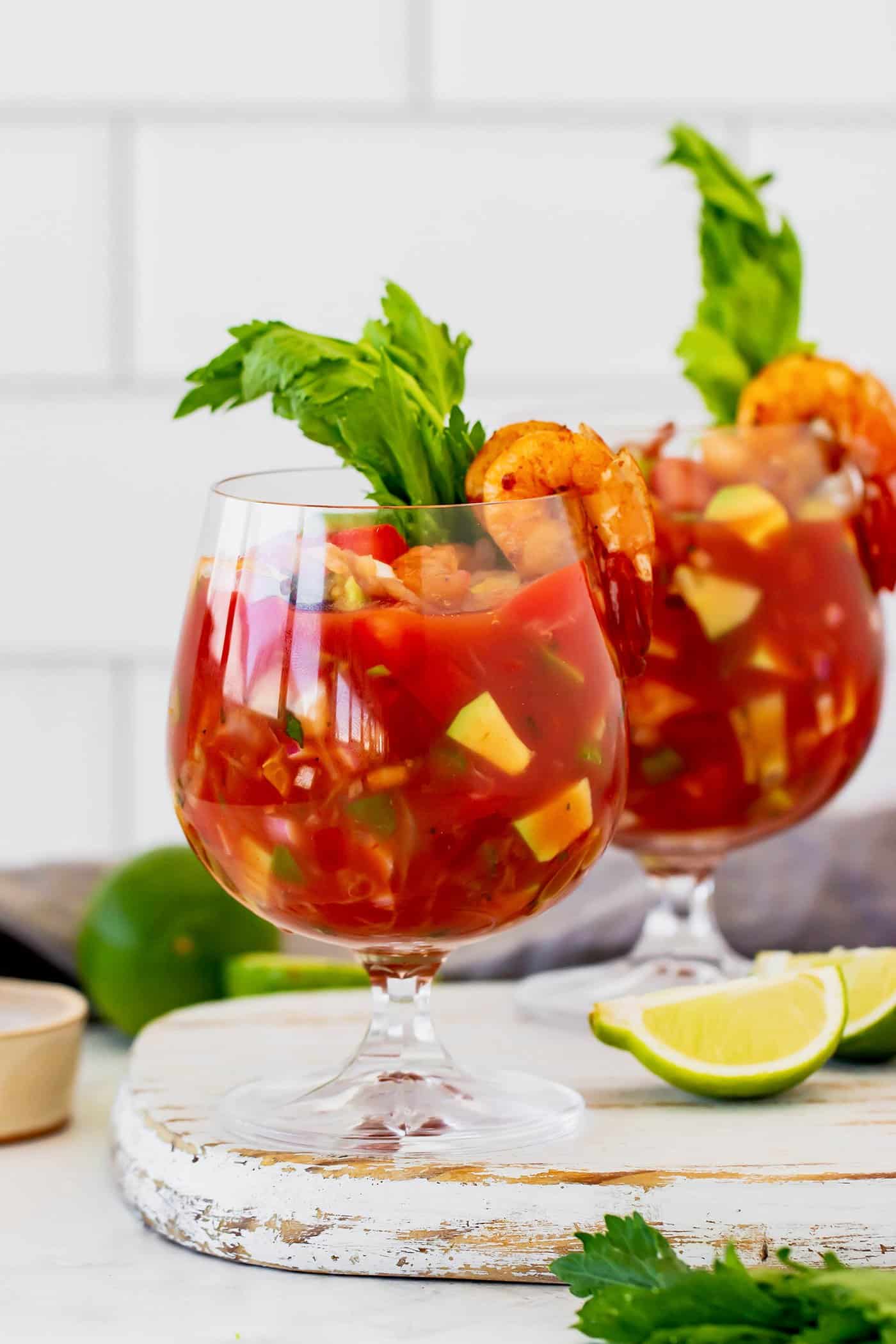 two stemmed glasses with Mexican shrimp cocktail, plus fresh limes