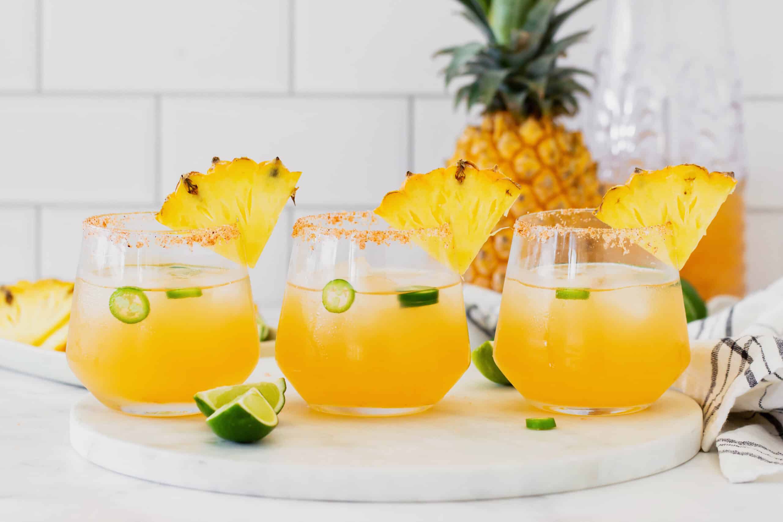 3 glasses of pineapple jalapeno margaritas, arranged in a straight row