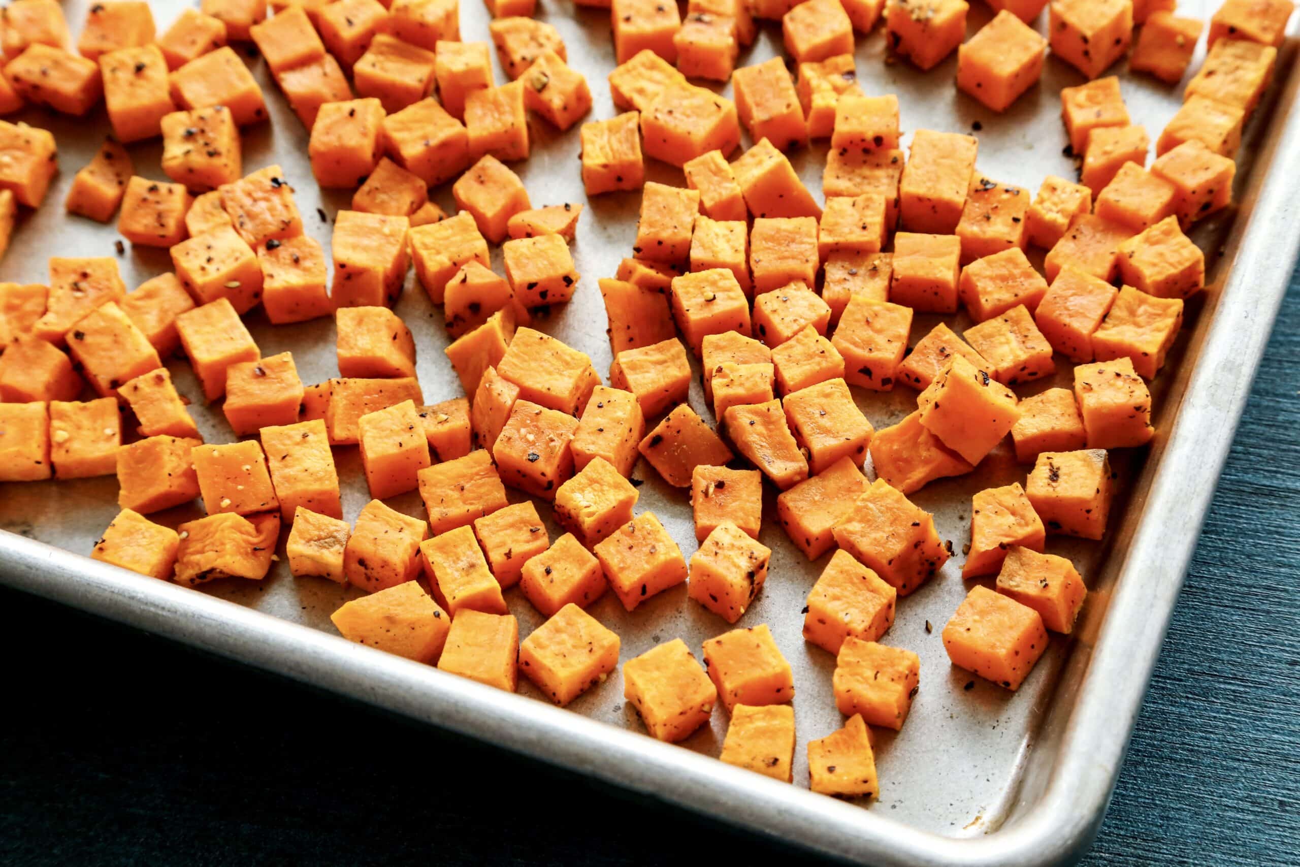 roasted cubes of sweet potatoes on a rimmed metal sheet pan