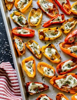 mini sweet peppers that were grilled and then filled with goat cheese, on a sheet pan