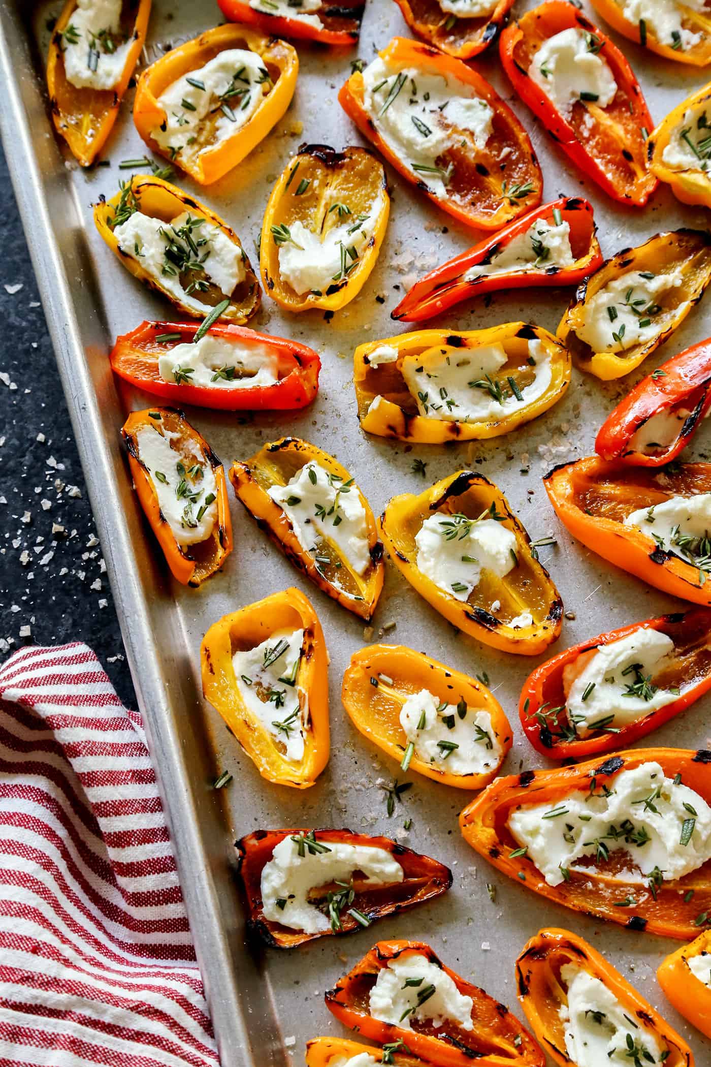 mini sweet peppers that were grilled and then filled with goat cheese, on a sheet pan