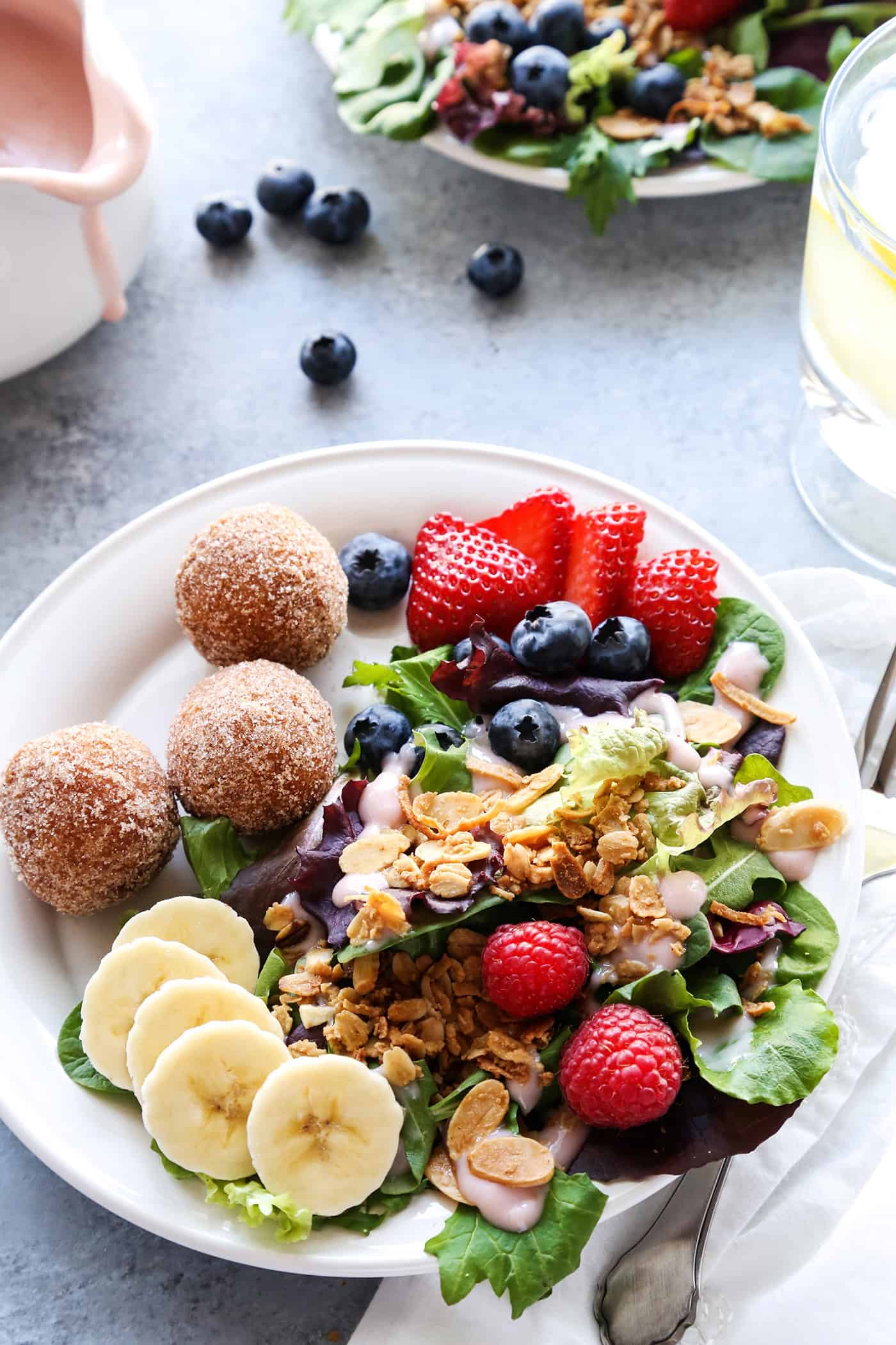 Berry Breakfast salad on a plate topped with granola with a few donut holes