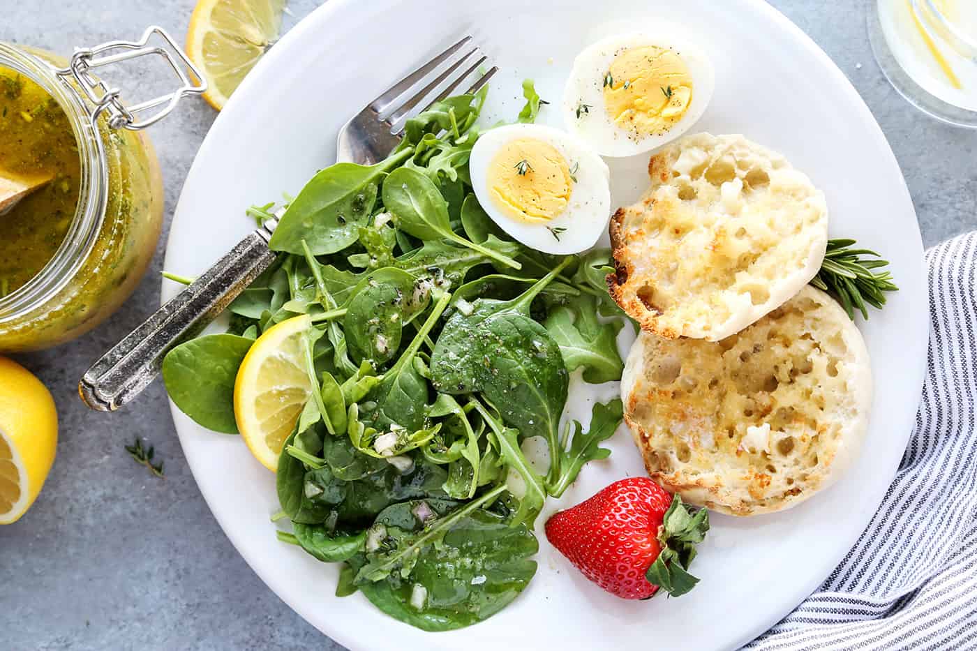 Overhead view of a plate of breakfast salad with a toasted English muffin and hard-boiled egg halves