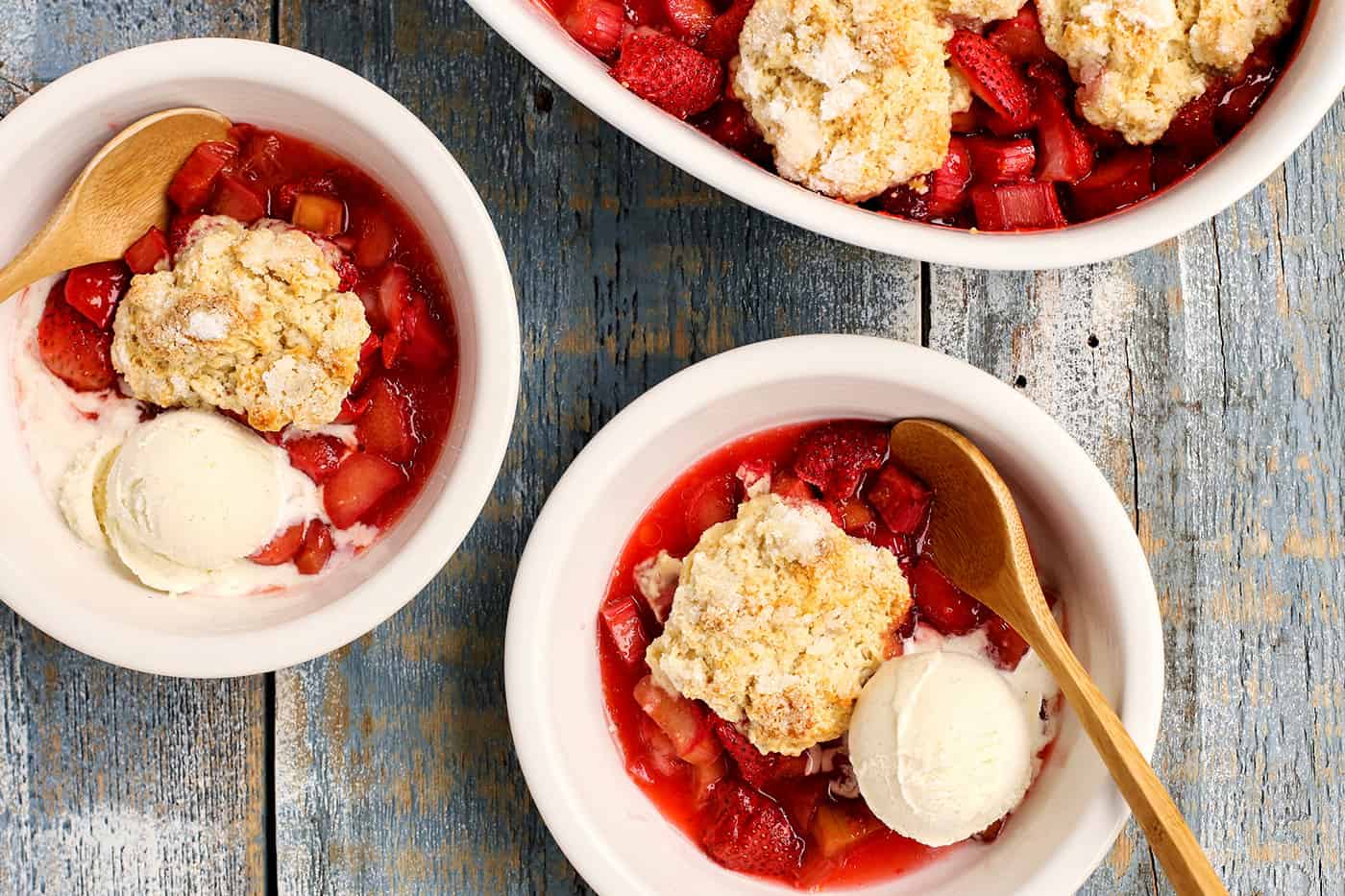 Overhead view of two servings of Strawberry Rhubarb Cobbler in bowls with vanilla ice cream