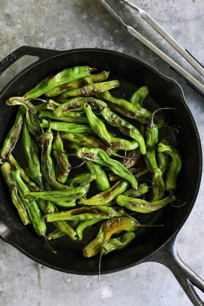 blistered shishitos in a cast iron skillet
