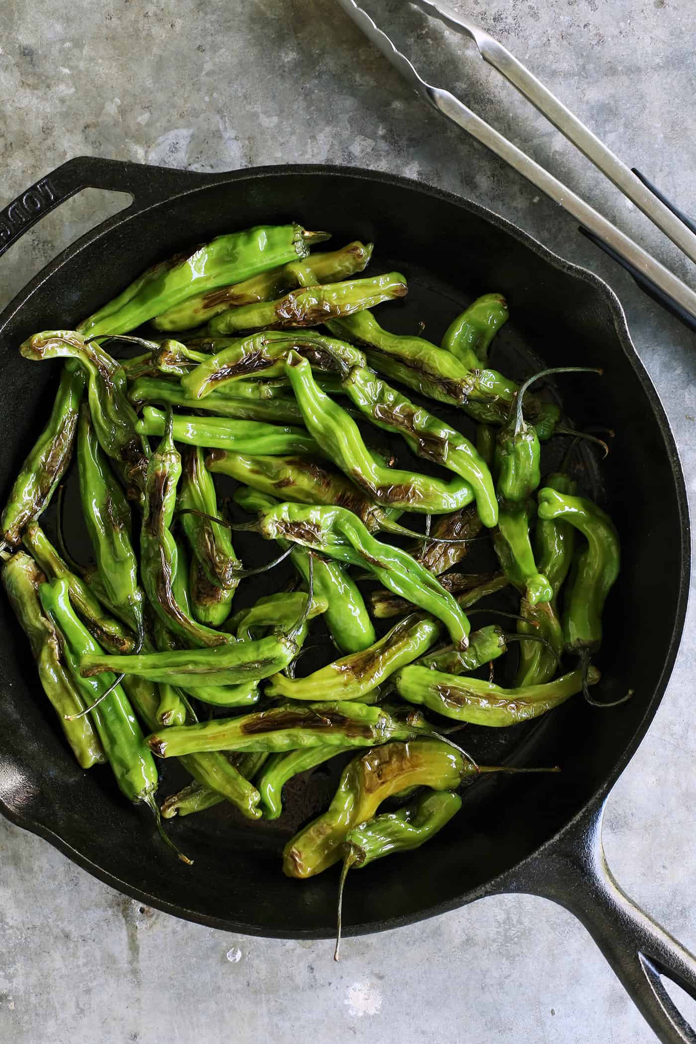 blistered shishitos in a cast iron skillet