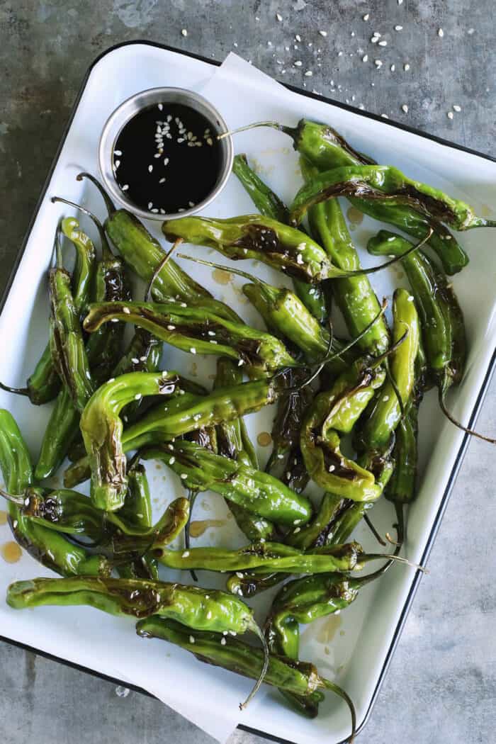 blistered shishitos on a rectangular white enamel pan