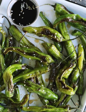 blistered shishitos on a white enamel tray with soy dipping sauce