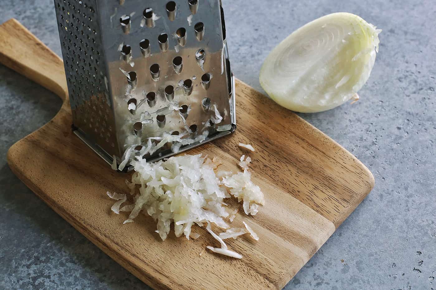 grating a yellow onion on a box grater