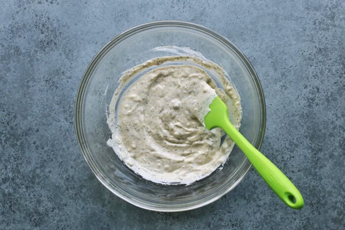 coleslaw dressing in a clear bowl, with a green spatula