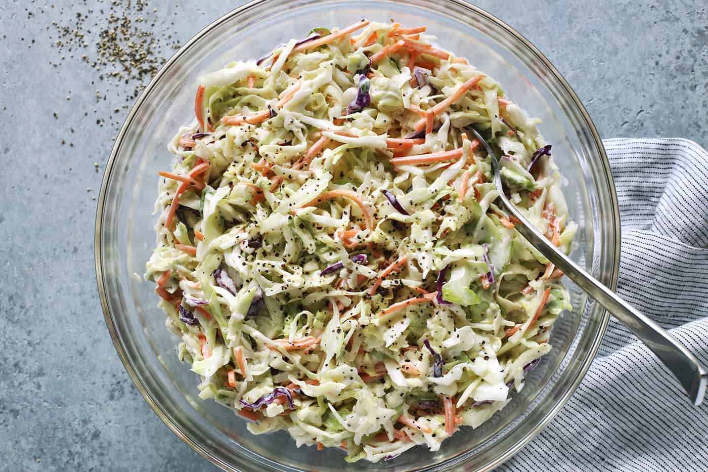 fresh shredded cabbage and carrots dressed with a mayo and sour cream based dressing, in a clear bowl