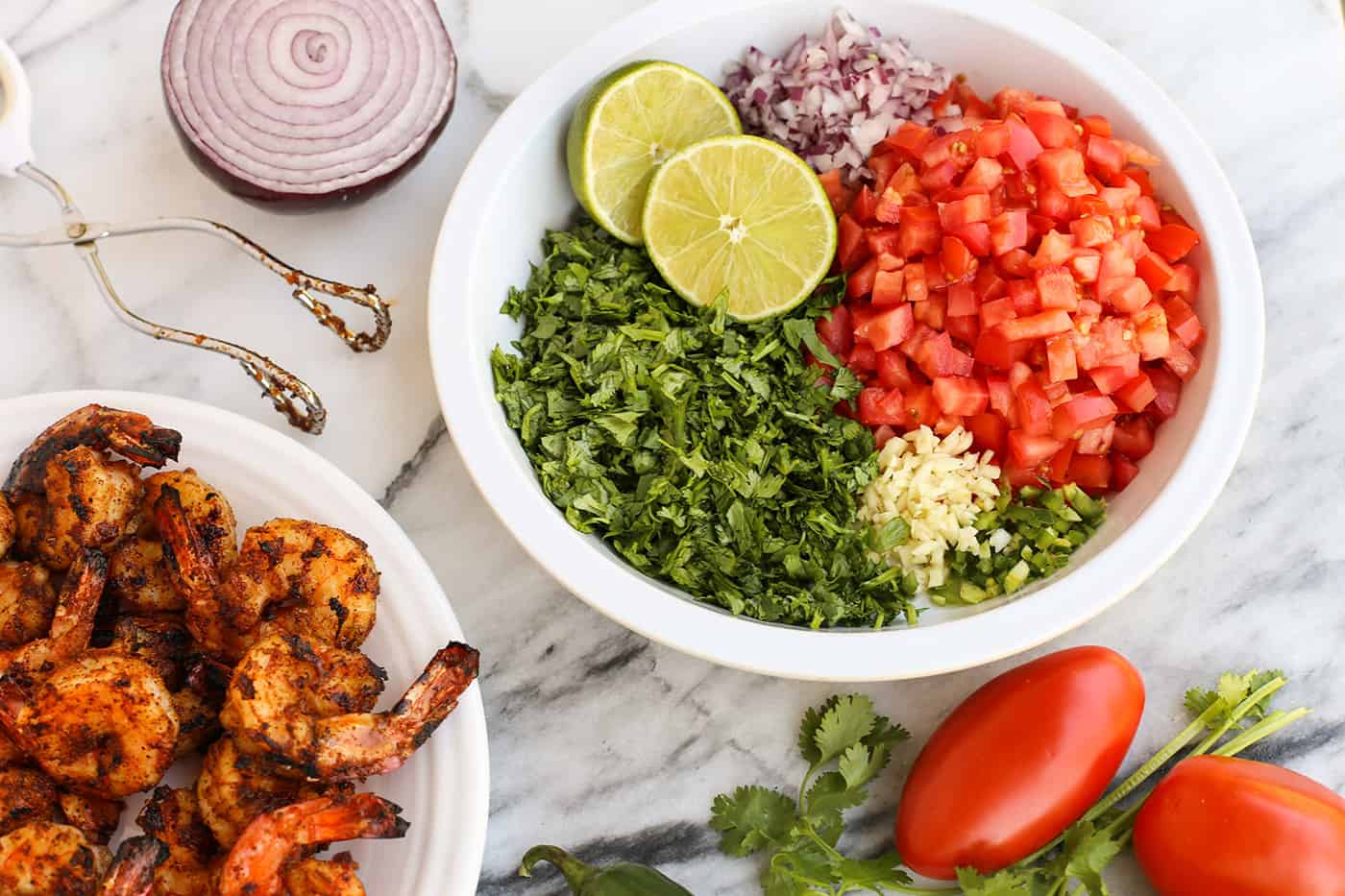 Overhead view of a bowl of diced ingredients for Shrimp Ceviche next to a bowl of seasoned grilled shrimp