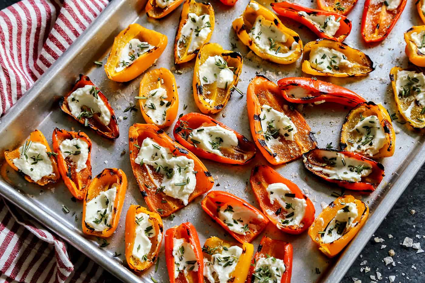 Overhead view of Grilled Mini Sweet Peppers filled with Goat Cheese on a sheet pan