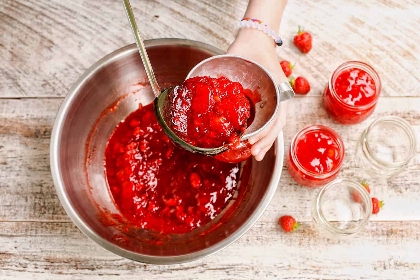 Strawberry jam being ladled into jars