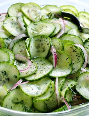 cucumber salad with vinegar in a clear bowl with a spoon