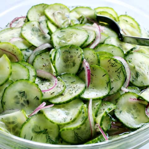 cucumber salad with vinegar in a clear bowl with a spoon