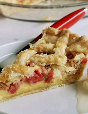 a slice of rhubarb custard pie on a white plate with a scoop of ice cream