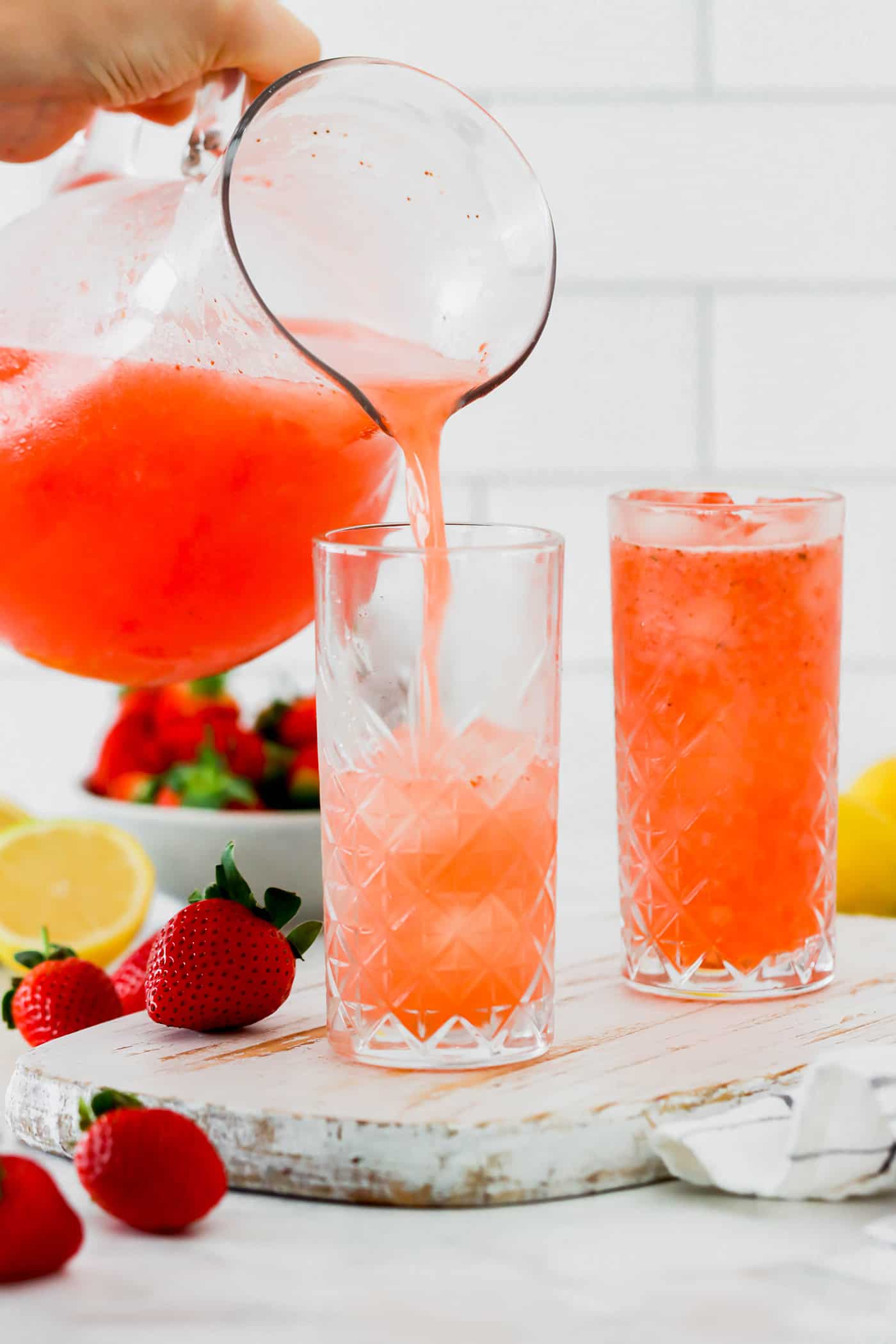 pouring strawberry lemonade from a pitcher into glasses