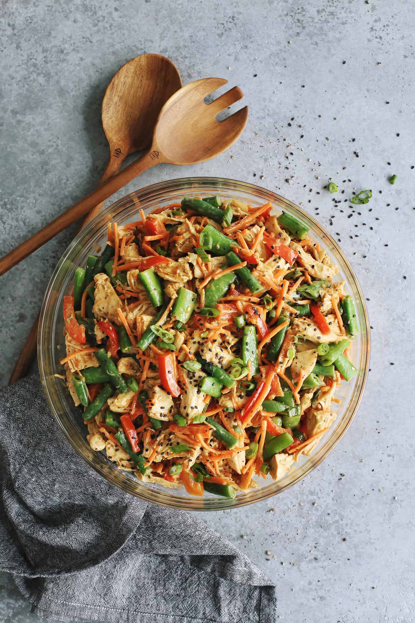 large clear bowl of Chinese chicken salad, plus a set of wooden salad tongs