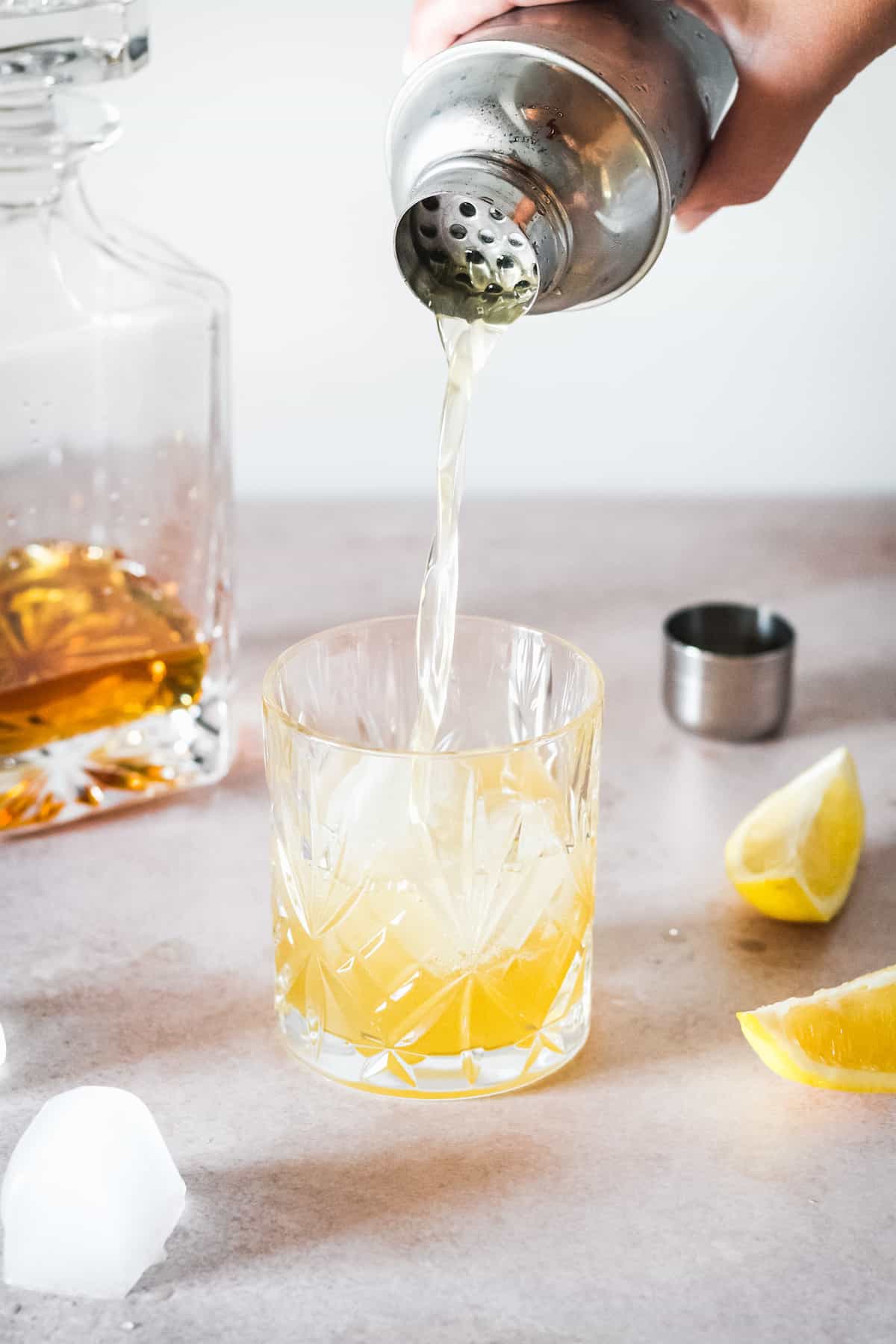 Bourbon sour being poured into a glass over ice