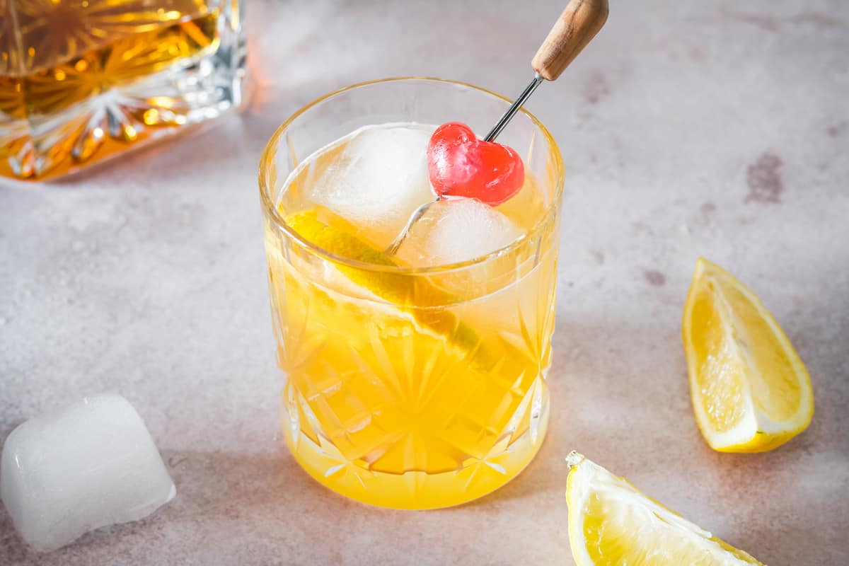 A bourbon sour garnished with a cherry and orange slice