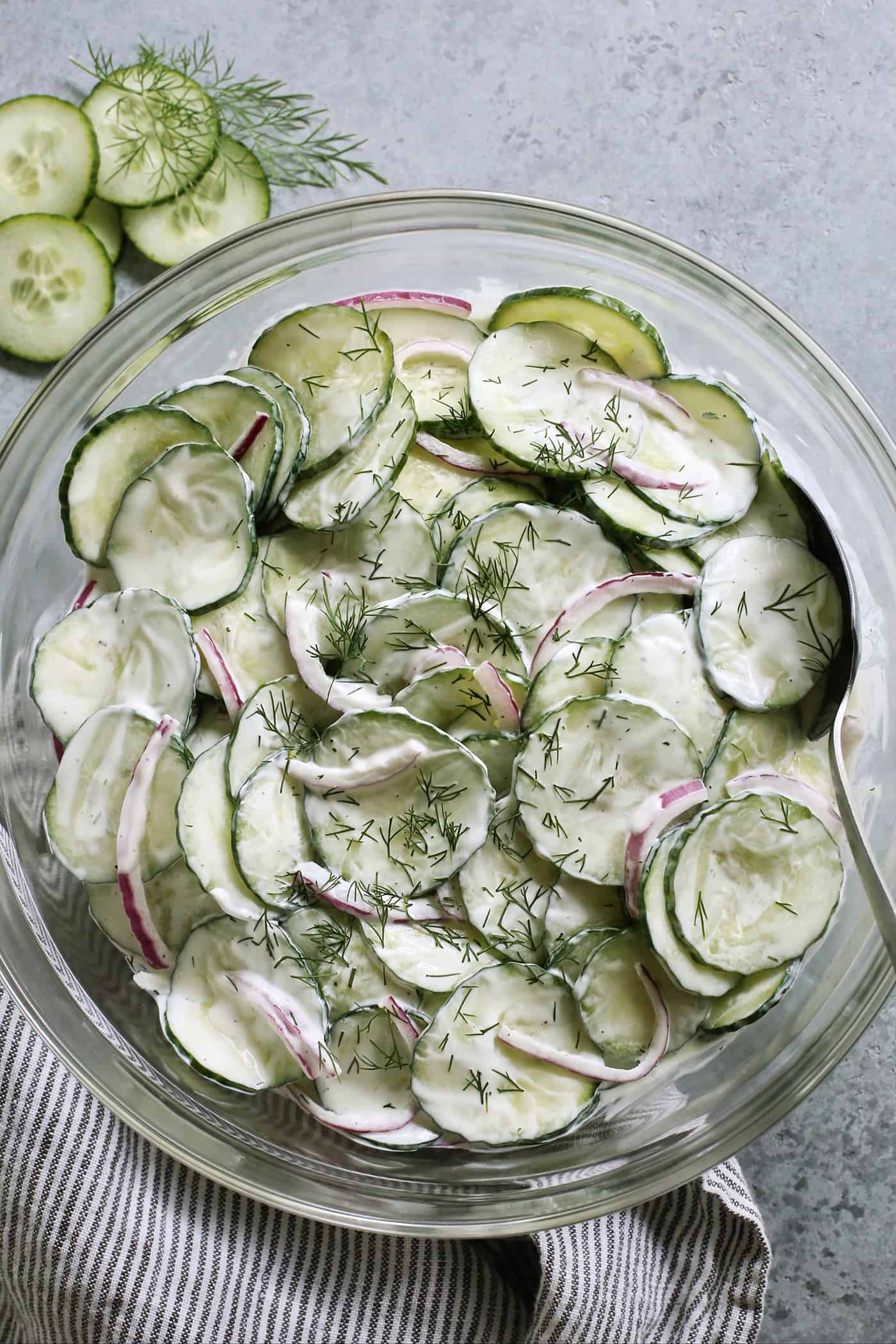 a large clear serving bowl of creamy cucumber salad