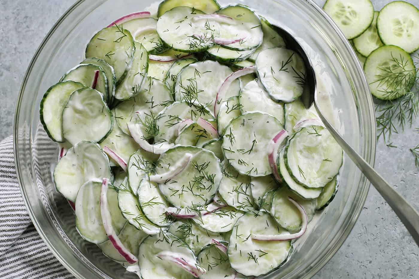 creamy cucumber onion salad with chopped fresh dill in a clear serving bowl