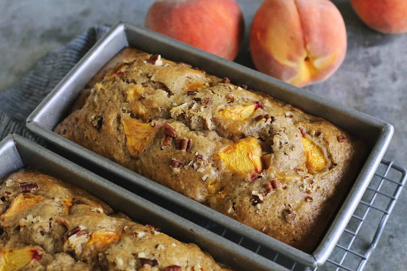 two pans of peach bread, plus a few fresh peaches