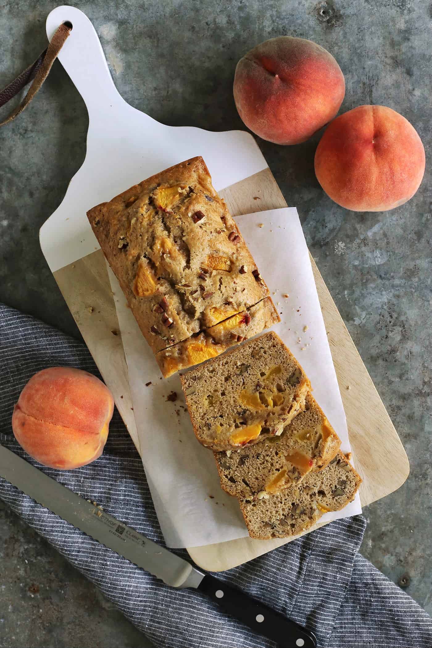 a cutting board with a loaf of peach bread that is partially sliced