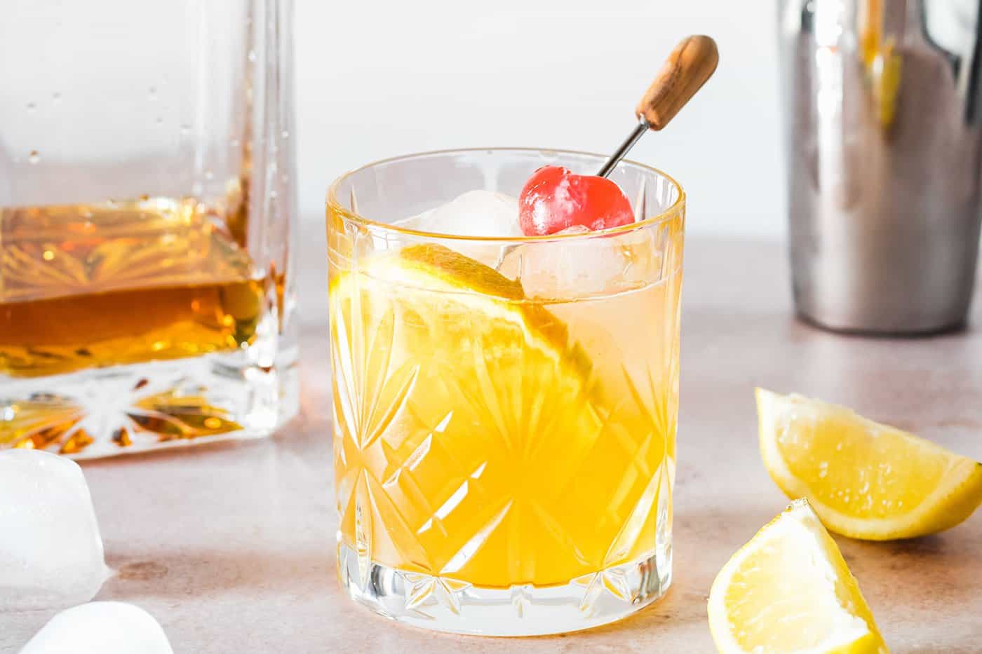 a classic whiskey sour made without egg white, garnished with an orange slice and cherry