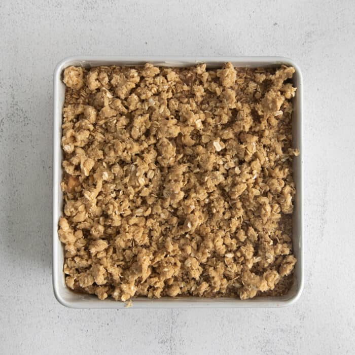 streusel topping shown on top of apple oatmeal, unbaked in a white square dish