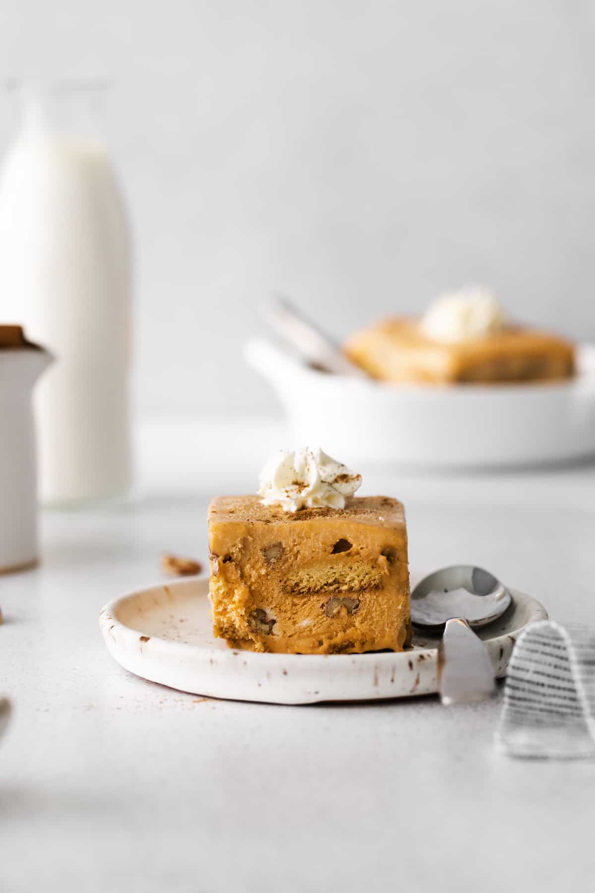 Square of Pumpkin Icebox Cake on plate with spoon, topped with whipped cream