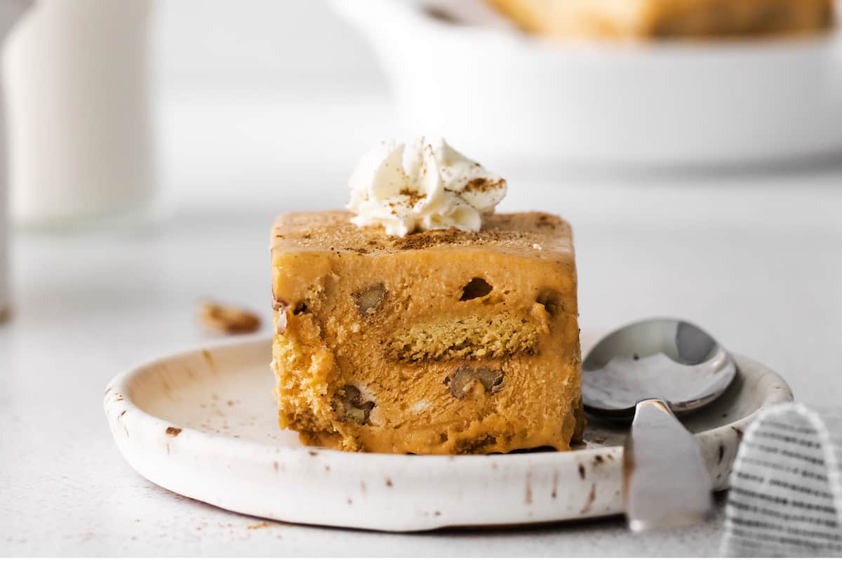 Closeup of Pumpkin Icebox Cake on plate with spoon, topped with whipped cream
