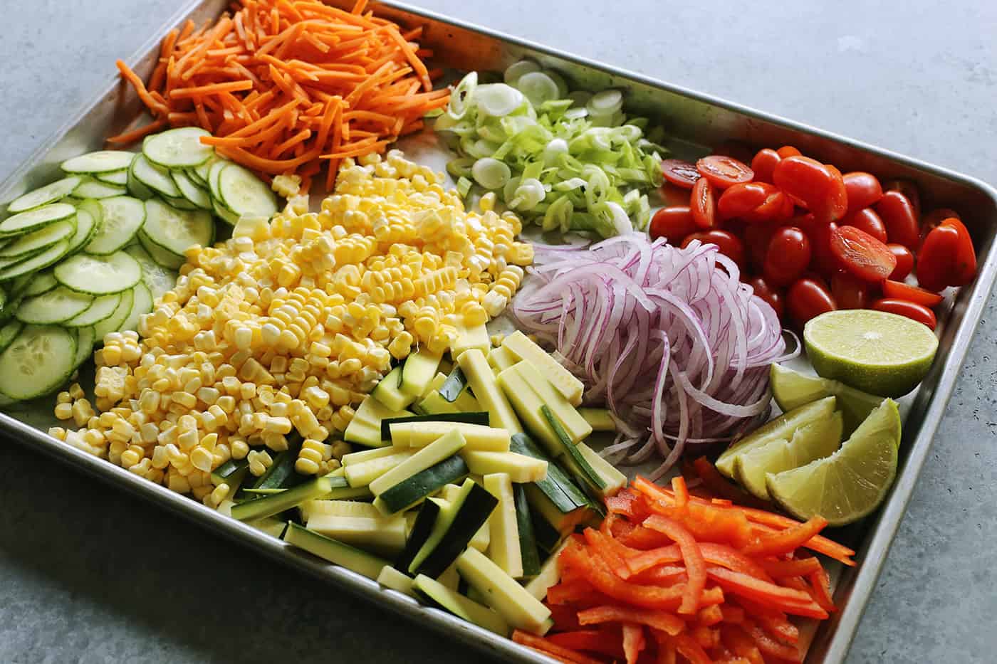 a large rimmed pan full of chopped and sliced fresh vegetables