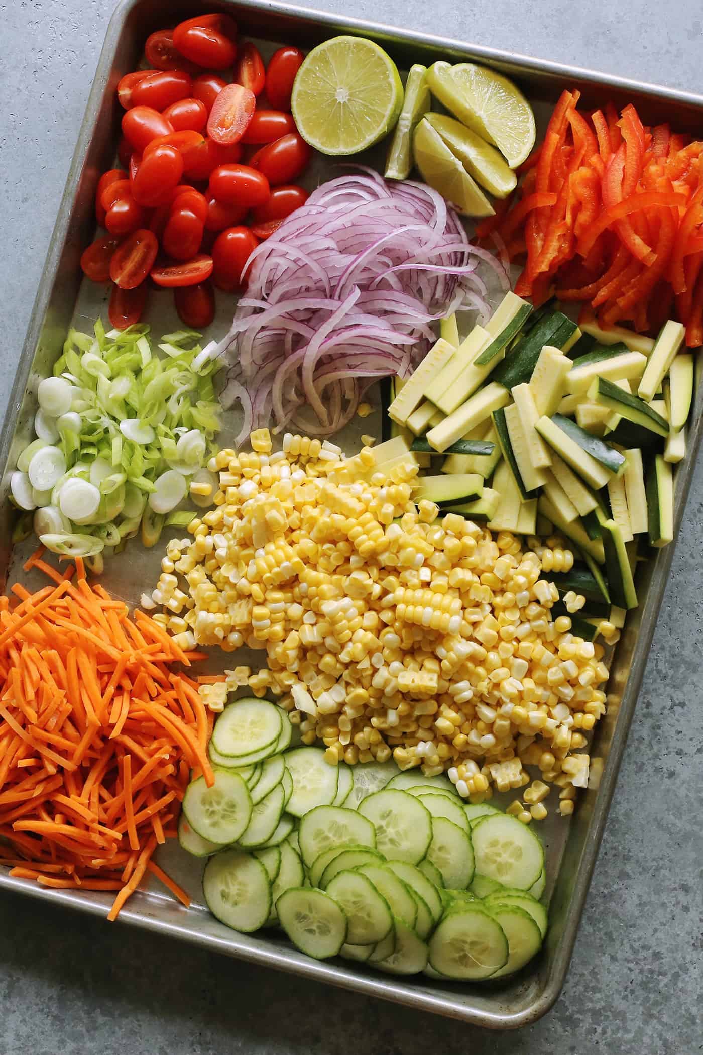 a large rectangular rimmed pan full of chopped and sliced fresh vegetables