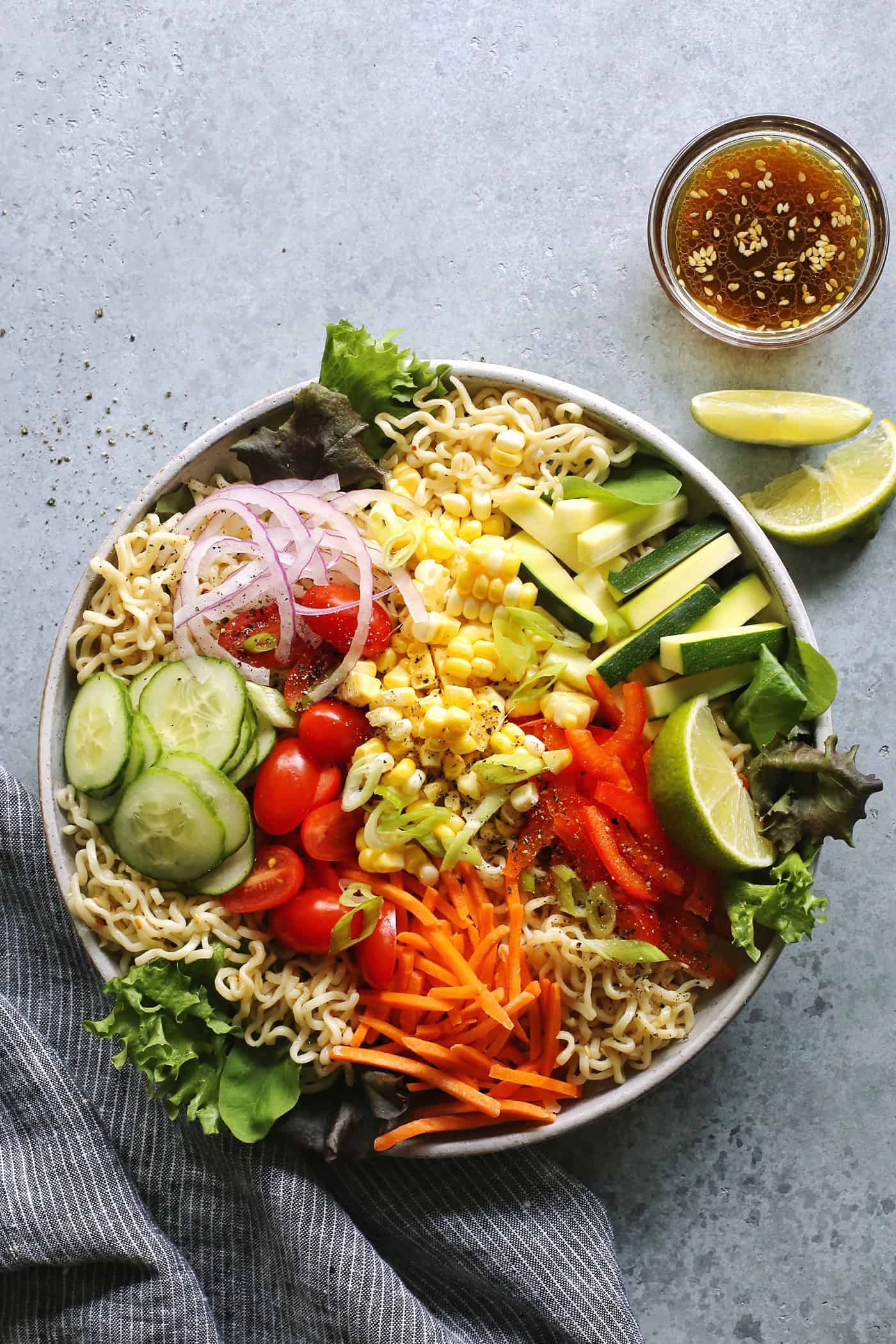 salad ramen in a light gray bowl with a cup of dressing on the side