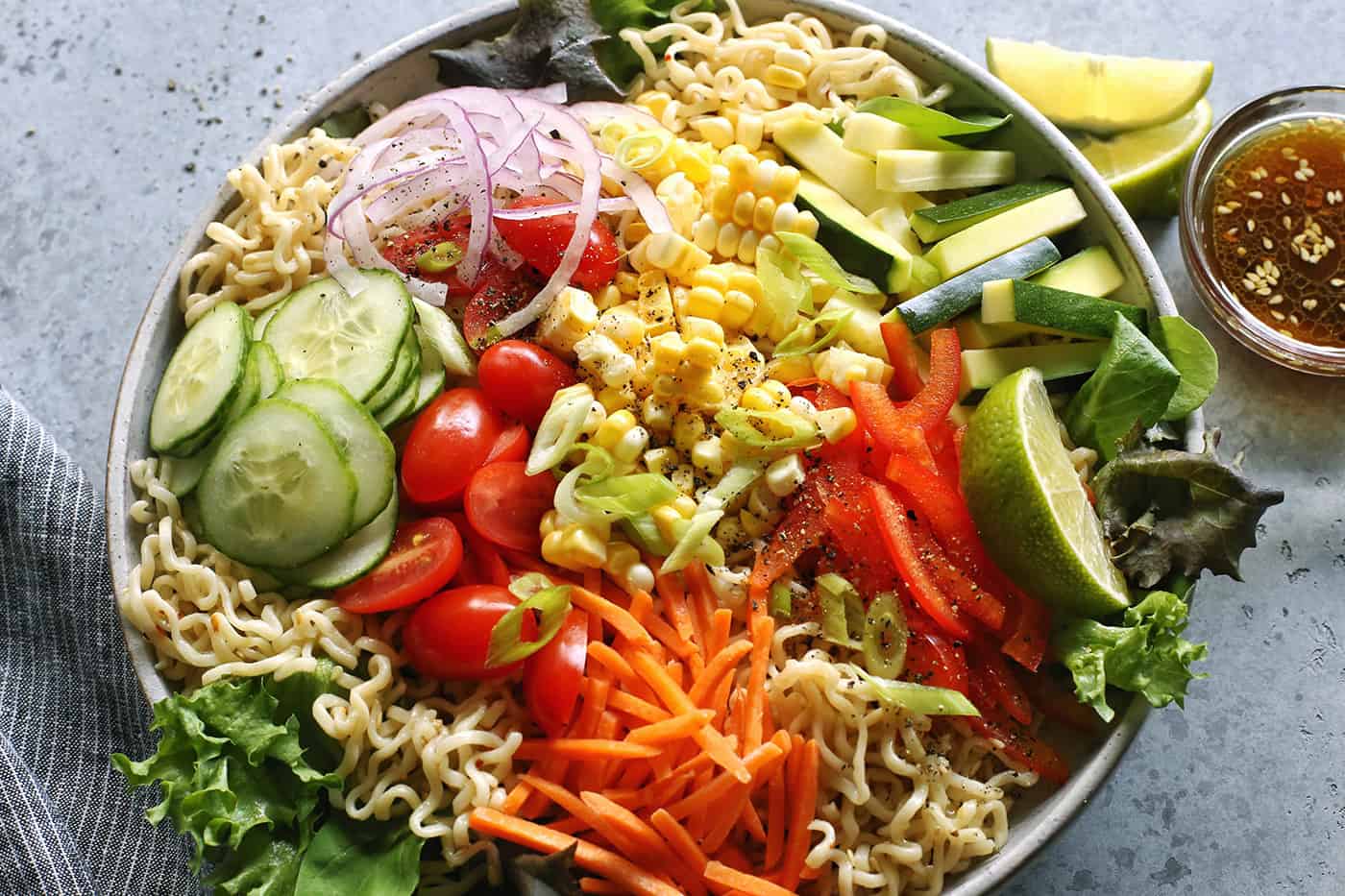 a light gray bowl full of veggies and ramen noodles